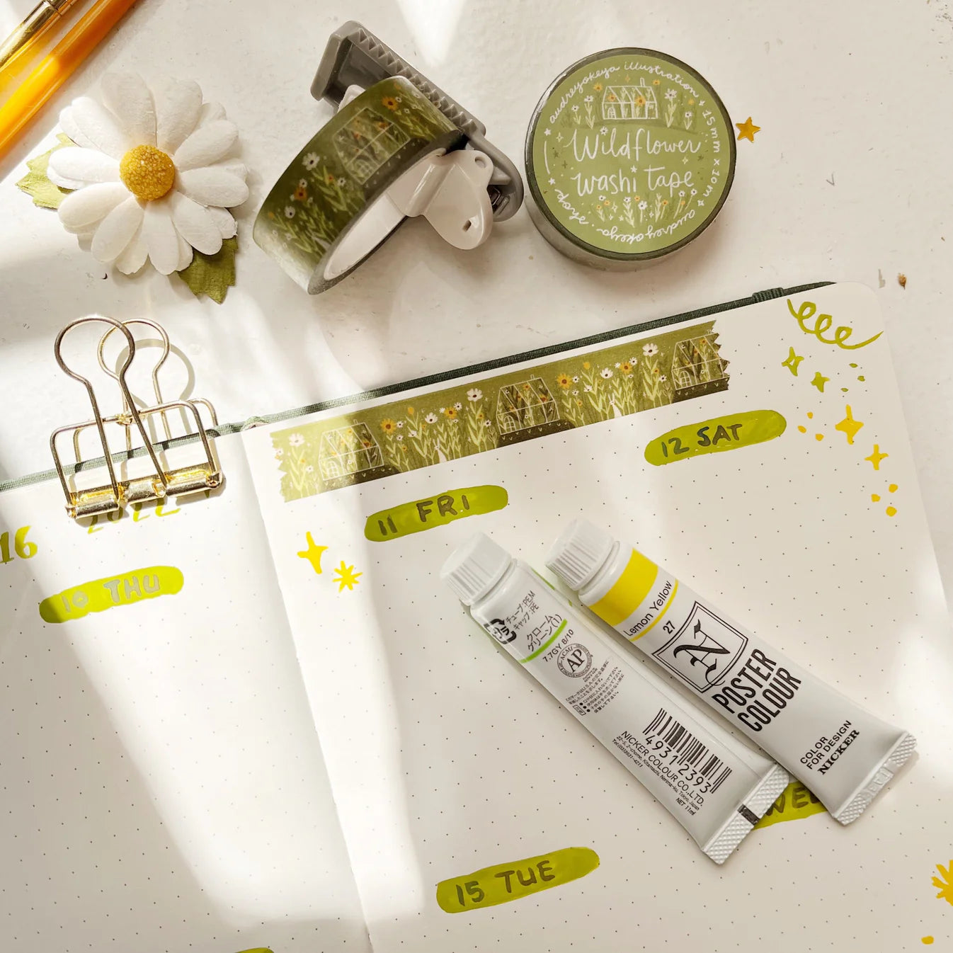 Stationery items including a notebook, glue sticks, and tape on a white surface with decorative elements.