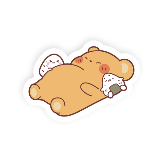 A cute cartoon die-cut sticker of a sleeping tan bear holding two white rice balls, shown on a plain white background.
