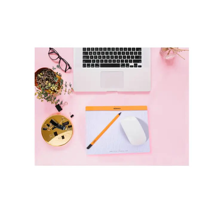 Laptop on a pink surface with office supplies including a pencil, mouse, and glasses.