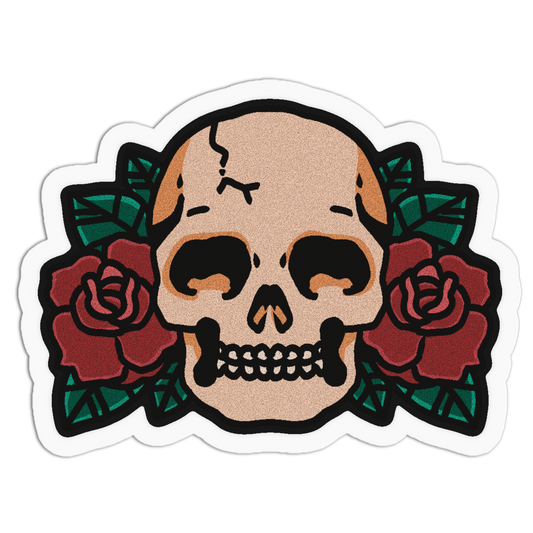 A die-cut sticker featuring a traditional tattoo-style skull centered between two red roses with green leaves, outlined in black and shown on a white background.