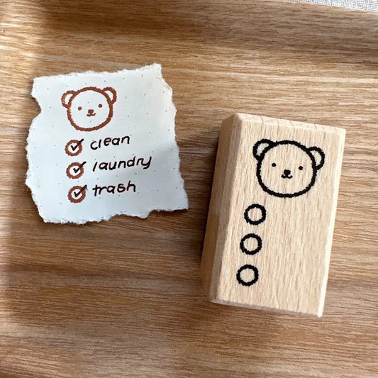 Wooden stamp with bear design and a piece of paper with checkboxes on a wooden surface