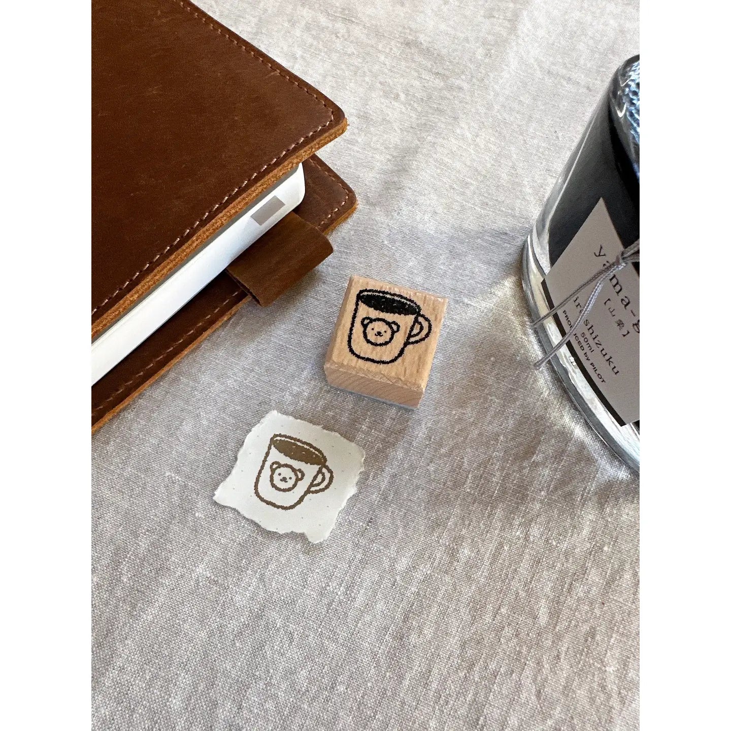 Rubber stamp with a coffee cup design on a textured surface next to a ink pad.