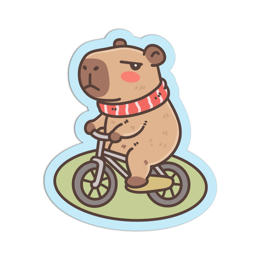 A cartoon sticker-style illustration of a capybara riding a small bicycle, shown on a plain white background. The capybara is tan with brown ears and face, wearing a red-and-white striped scarf, and the bicycle sits on a light green oval patch with a pale blue outline.
