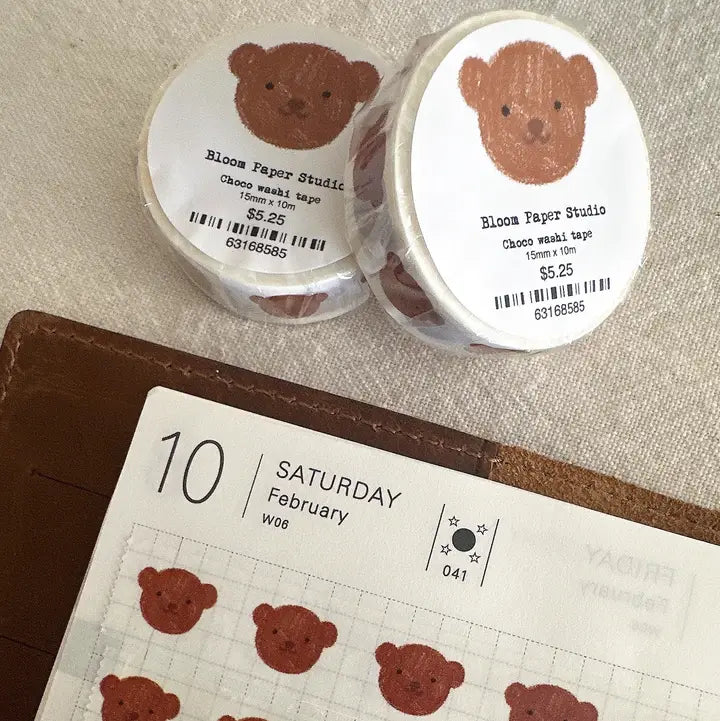 Two rolls of tape with bear designs and a calendar with bear stickers on a textured surface.