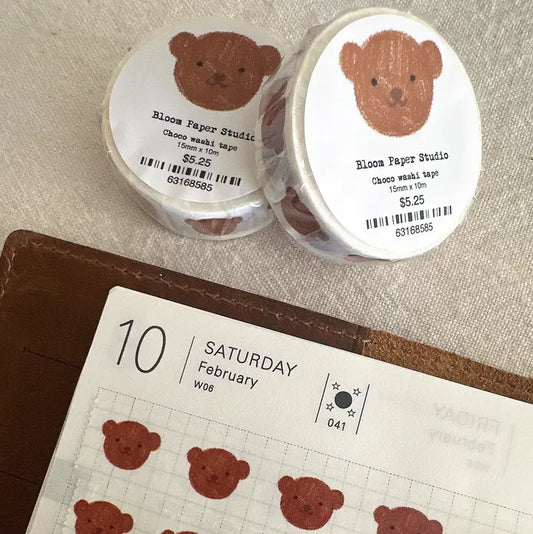 Two rolls of tape with bear designs and a calendar with bear stickers on a textured surface.