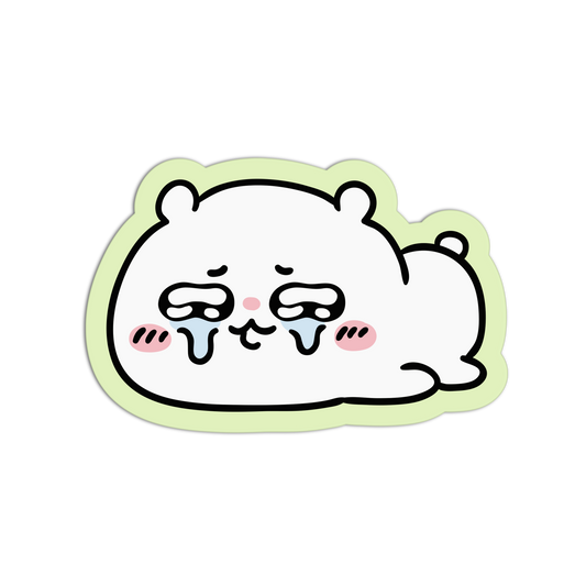 A die-cut sticker featuring a cute, white cartoon character with closed eyes, tears, pink cheeks, and a light green border, shown on a plain white background.