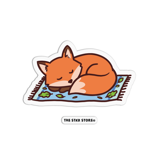 Sticker of a sleeping fox on a rug with 'The Stkr Store' logo.