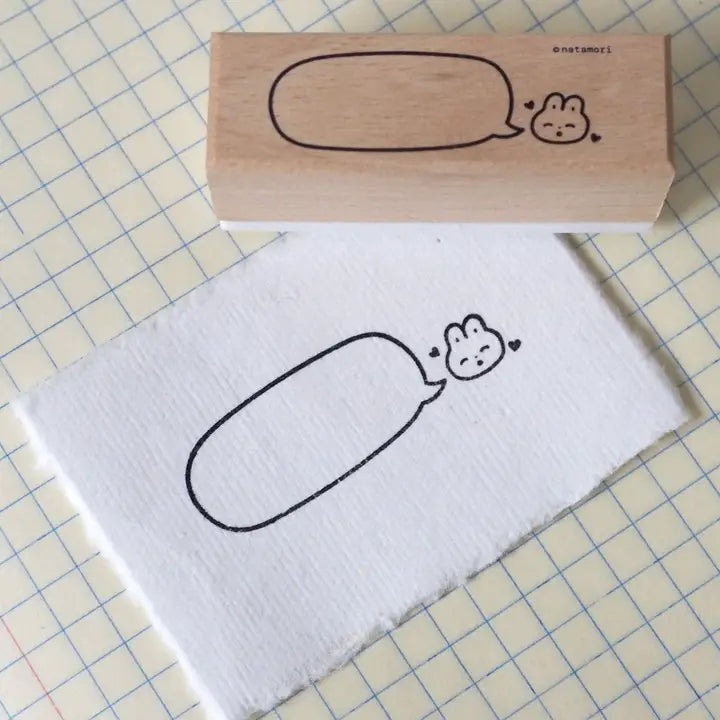 Wooden stamp with a cartoon design on a piece of paper with grid lines.