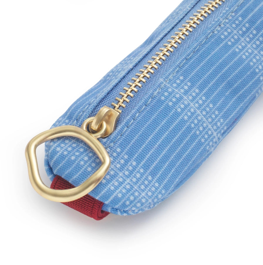 Close-up of a blue textured pouch with a gold zipper and red pull tab on a white background