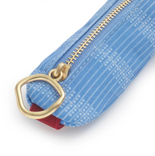 Close-up of a blue textured pouch with a gold zipper and red pull tab on a white background