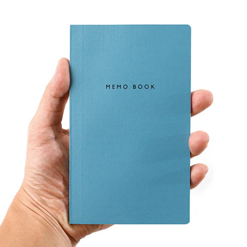 Hand holding a blue memo book with 'MEMO BOOK' text on a white background