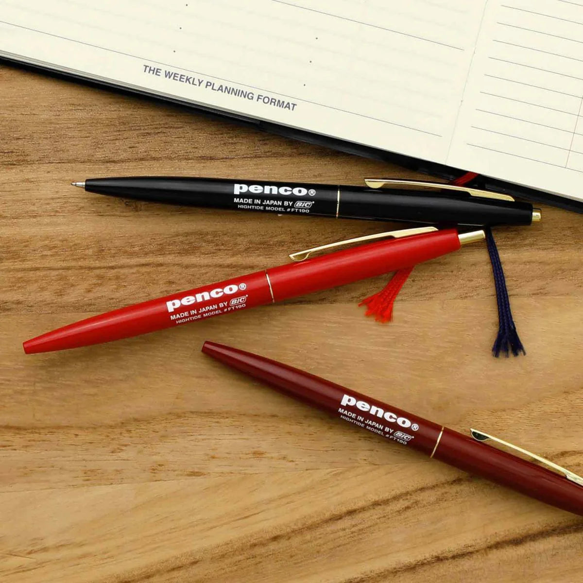 black red and burgundy pens on wooden table