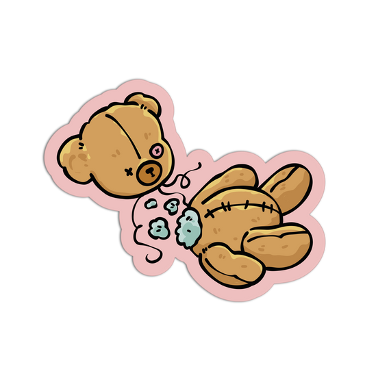 A die-cut sticker featuring a cartoon illustration of a stitched brown teddy bear lying on its side with a light blue bandage and a pink outline, shown on a plain white background.