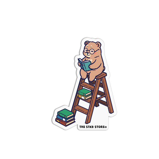 Sticker of a bear reading a book on a ladder with 'The Stkr Board' logo.
