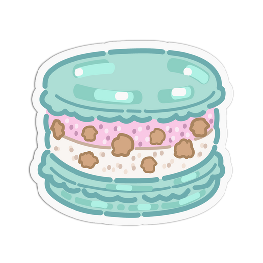 A die-cut sticker featuring a cute, stylized illustration of a French macaron with a light blue top and bottom, a pink polka-dotted middle layer, and brown cookie crumbs, shown on a plain white background.