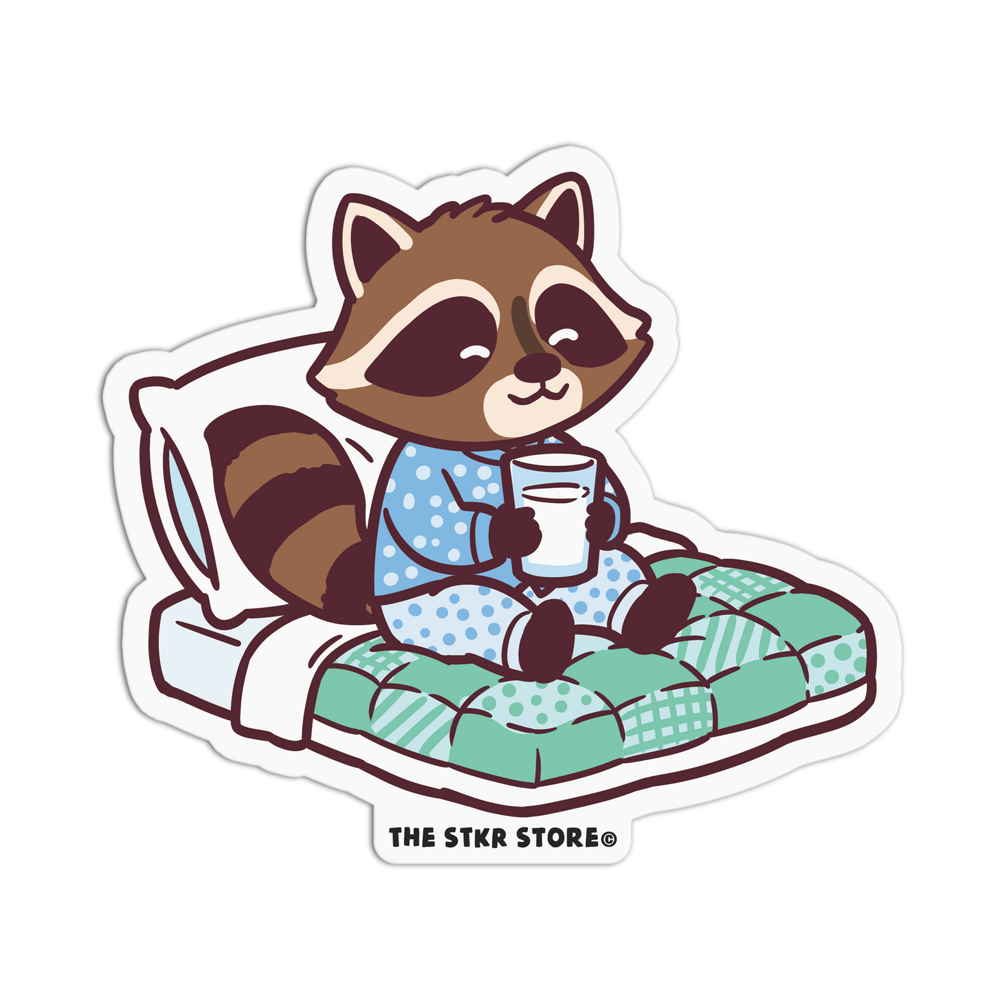 Sticker of a raccoon in pajamas holding a mug on a pillow with 'The Stkr Store' logo.