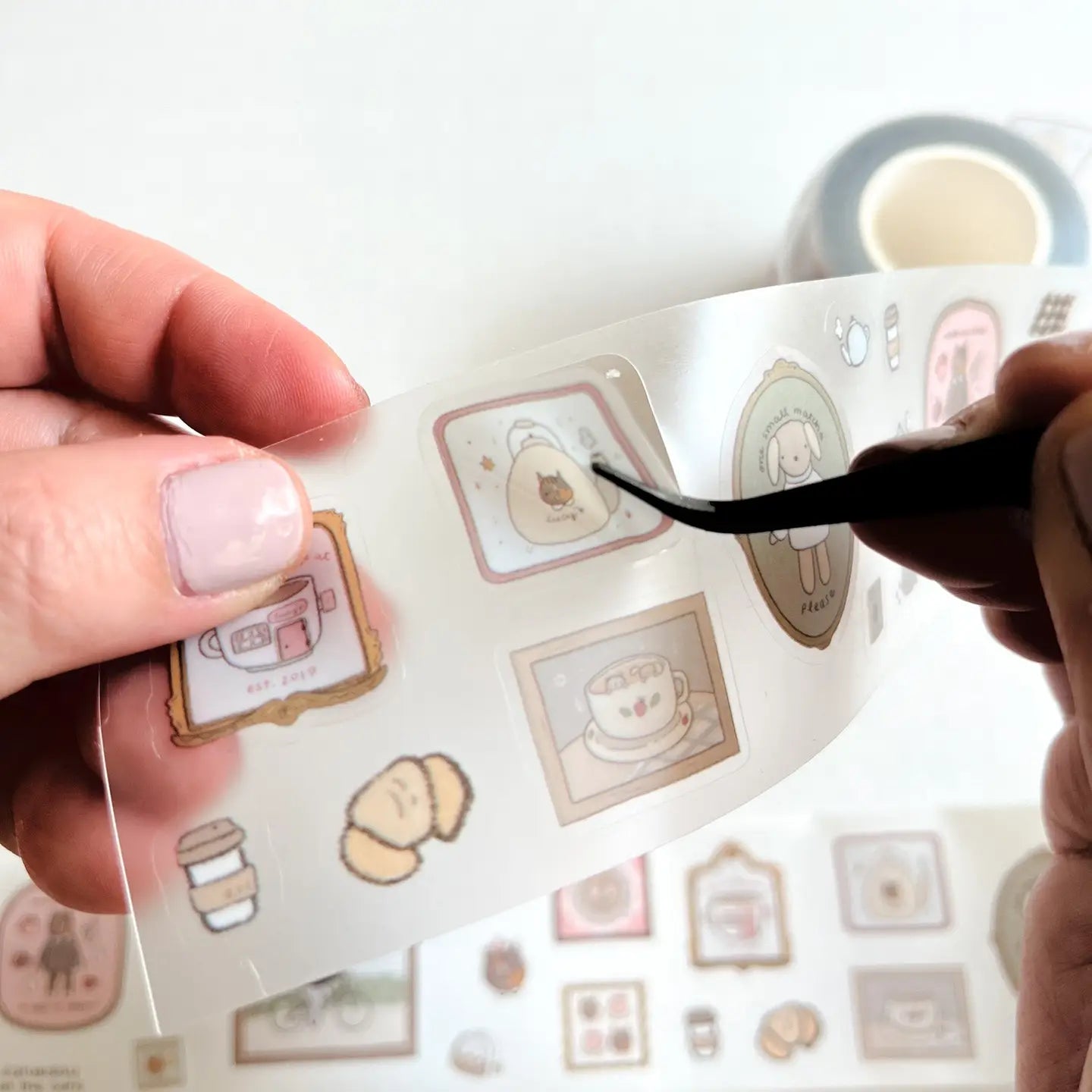 Hand holding a roll of decorative tape with cute illustrations
